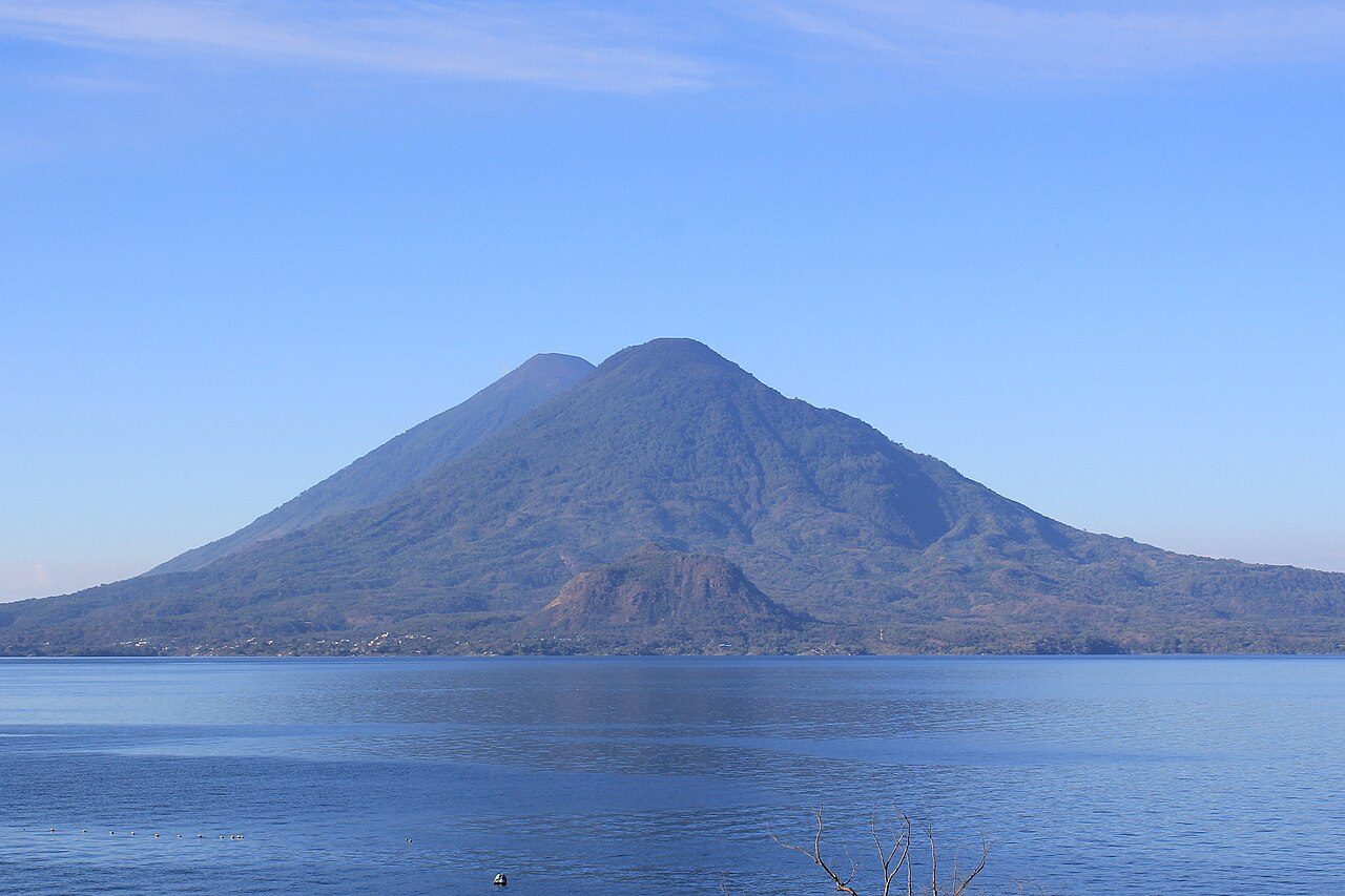 A vast volcanic lake ringed by cones, seen from its shore
