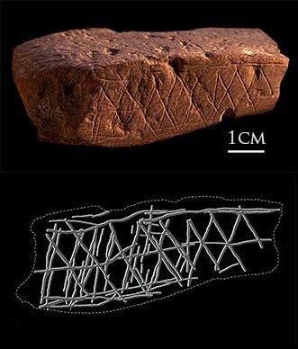 A reddish ochre stone with a cross-hatched pattern scored into its face