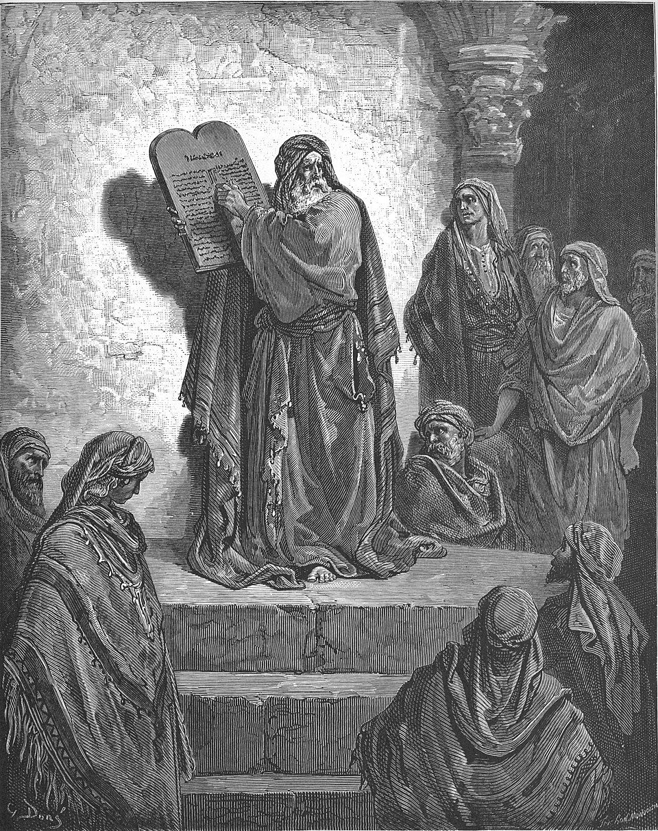 Ezra stands on a wooden pulpit reading the law to an assembled crowd.